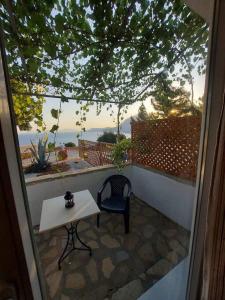 a table and a chair on a balcony with a view at Beautiful house located on a hill in Samos Island, 400 m from an organized beach in Koumeika