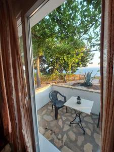 a table and chair on a patio with a view of the ocean at Beautiful house located on a hill in Samos Island, 400 m from an organized beach in Koumeika