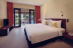 a bedroom with a large white bed and a television at Mercure Resort Sanur in Sanur