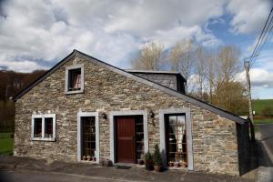 una piccola casa in pietra con due finestre e un tetto di Une parenthèse en Ardenne a Nollevaux
