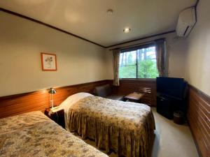 Petit Hotel Kazekozou في Shinano: غرفة فندقية بسريرين ونافذة