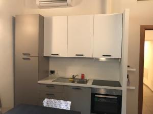 una cocina con armarios blancos y fregadero en Appartamento Gloria, en Cremona