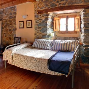 a bedroom with a bed and a stone wall at Casa Susarón in Puebla de Lillo
