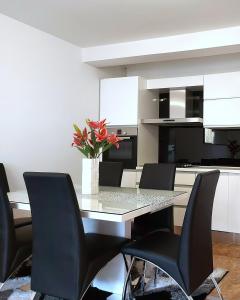 a dining room table with black chairs and a vase of flowers at Deluxe Apartment MyPlace in Osijek
