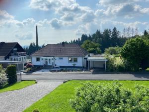 ein großes weißes Haus mit Auffahrt in der Unterkunft BUCHLINDENWEG - Zimmer & Ferienwohnung in Breitscheid