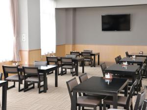a dining room with tables and chairs and a flat screen tv at Takasago Onsen in Asahikawa