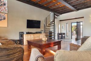 a living room with a wooden table and a tv at Atlantic Links Estate by AirAgents in Cape Town
