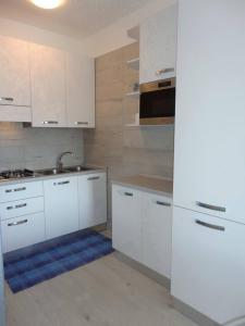 uma cozinha com armários brancos e um lavatório em Modern flat for 6 with shared pool em Porto Santa Margherita di Caorle