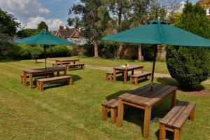 a picnic table with chairs and umbrellas in a grassy area at Best Western Plus Oxford Linton Lodge in Oxford