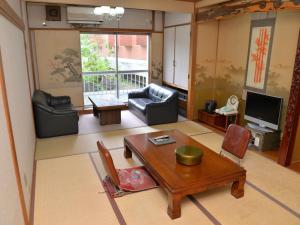 a living room with a table and chairs and a television at Takasago Onsen in Asahikawa