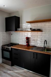 een keuken met zwarte kasten, een wastafel en een fornuis bij Ikaros Art Hotel in Agios Nikolaos