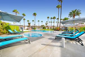 a pool with blue lounge chairs and a swimming pool at Relaxia Los Girasoles Bungalows in Playa del Ingles