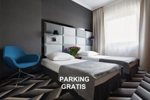 una habitación de hotel con 2 camas y una silla azul en Hotel Apis en Cracovia