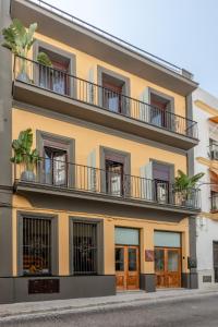 um edifício amarelo com janelas e varandas em Villamarta Boutique Rooms em Jerez de la Frontera