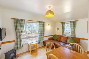 a living room with a couch and a table at Fern Lodge 11 with Hot Tub in Belladrum