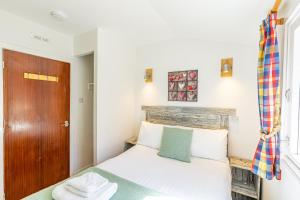 a small bedroom with a bed and a wooden door at Fern Lodge 11 with Hot Tub in Belladrum