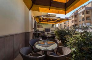 a patio area with tables, chairs and umbrellas at Hotel San Giuan in Alghero