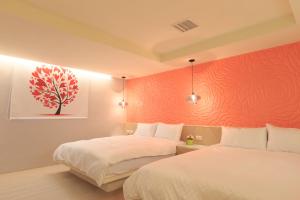 a bedroom with two beds and a red wall at Travelyoung Hotel in Kaohsiung