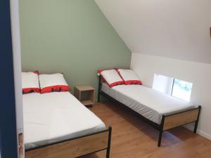 2 camas en una habitación pequeña con almohadas blancas y rojas en Gîte Lepetit Sabotier grande capacité Puy de Dôme, en Giat