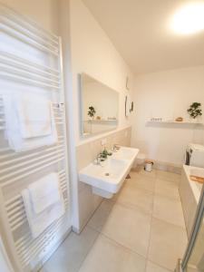 a white bathroom with a sink and a mirror at PB Ferienwohnungen - FeWo 7 - Stilvoll eingerichtetes Apartment im Herzen Senftenbergs in Senftenberg