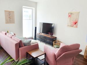 a living room with two pink couches and a television at PB Ferienwohnungen - FeWo 7 - Stilvoll eingerichtetes Apartment im Herzen Senftenbergs in Senftenberg