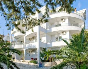 a white building with trees in front of it at Apartments Villa Kukoljac in Herceg-Novi