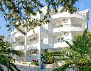 un edificio blanco con árboles delante de él en Apartments Villa Kukoljac, en Herceg-Novi