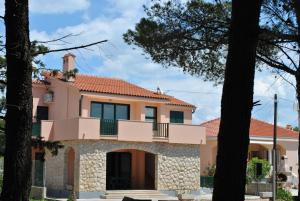 a house with a balcony and trees at Apartments Sunny Punta in Privlaka