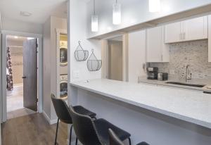 a kitchen with white cabinets and a counter with chairs at Breakaway West #212 condo in Vail +11 photos