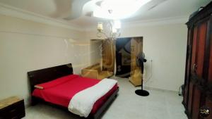 um quarto com uma cama com um cobertor vermelho e branco em شقة للإيجار اليومي أمام عمارات المحروسة لا ترى البحر 7 em Alexandria