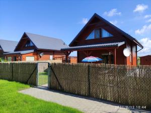 uma casa com uma cerca em frente em Przytulny domek em Darłówko