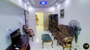 uma sala de estar com uma televisão, um sofá e uma cadeira em شقة للإيجار اليومي أمام عمارات المحروسة لا ترى البحر 7 em Alexandria