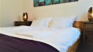 Una cama con sábanas blancas y toallas. en Napocska Vendégház Harkány, en Harkány