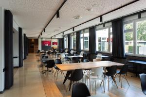 eine Cafeteria mit Tischen, Stühlen und Fenstern in der Unterkunft aletto Hotel Kudamm in Berlin