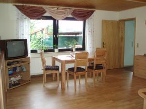 ein Esszimmer mit einem Tisch, Stühlen und einem TV in der Unterkunft Ferienwohnung-Jung in Bad Sachsa