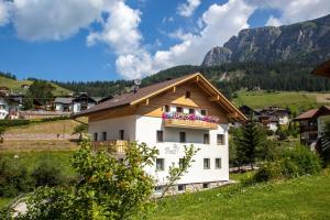 a house on a hill with flowers on a balcony at Appartamento Puez in Selva di Val Gardena