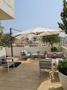 a patio with couches and an umbrella on a roof at D Townhouse Boutique Suites in Sliema