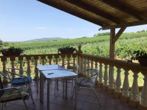 a table and chairs on a balcony with a view of a vineyard at Joe Bácsi Rezidenciája in Kisharsány