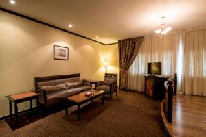 Rolla Suites Hotel -Former J5 Bur Dubai Hotel في دبي: غرفة معيشة بها أريكة وتلفزيون