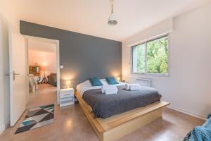 ein Schlafzimmer mit einem Bett mit blauen Kissen und einem Fenster in der Unterkunft Coeur du village-Appartement refait a neuf, Une Exclusivité LLA Selections by Location lac Annecy in Saint-Jorioz