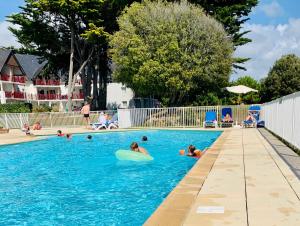 un gruppo di persone che nuotano in una piscina di Appartement dans résidence de standing avec terrasse et vue mer a Le Pouliguen