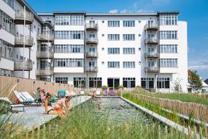 un grupo de personas en una piscina frente a un edificio en West Bay, en Middelkerke