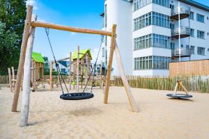 a playground with swings in the sand in front of a building at West Bay in Westende