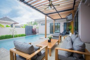 eine Terrasse mit einem Sofa, einem Tisch und einem Pool in der Unterkunft Gold Chariot Pool Villa, Phuket - SHA Plus Certified in Strand Bang Tao
