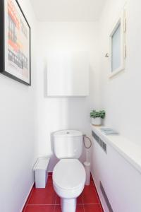 a bathroom with a white toilet and red floor at BRIGHT CHARMING Apt with TERRACE, PARKING & AirCo. in Prague