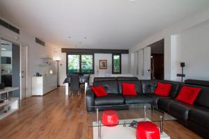 uma sala de estar com um sofá de couro preto e almofadas vermelhas em Club Villamar - Piamonte em Calonge