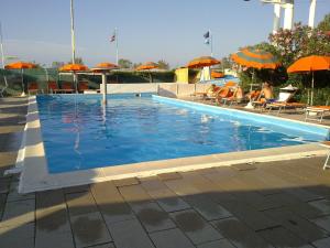 a swimming pool with umbrellas and people sitting in chairs at Hotel Emma Nord in Rimini