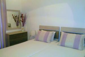 een slaapkamer met een wit bed met 2 kussens en een spiegel bij Katerinas House Apartment in Agios Gordios