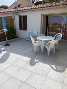 patio ze stołem, krzesłami i parasolem w obiekcie Location 5 personnes Sant Ambroggio Cocody village w mieście Lumio