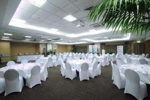 a banquet hall with white tables and white chairs at Quality Hotel Lincoln Green in Auckland